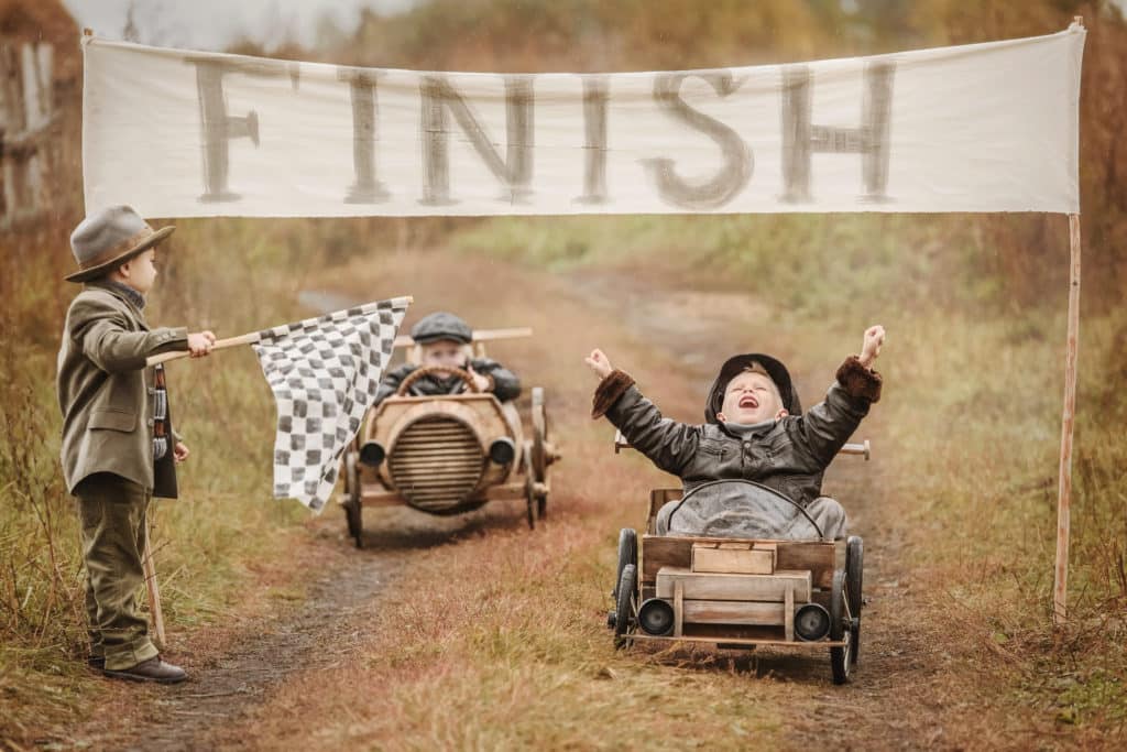 Two children racing in go karts crossing the finishing line.