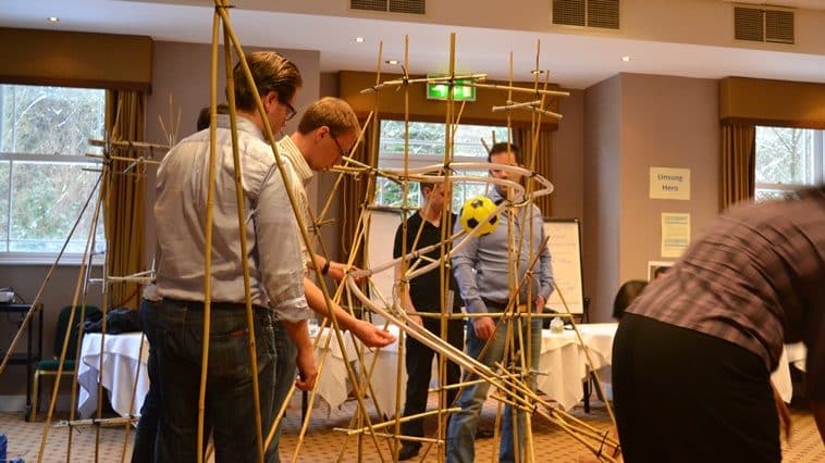 A team building a rollercoaster out of bamboo canes during an exercise