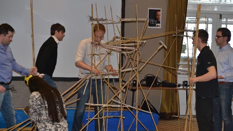 A team building a rollercoaster out of bamboo canes during an exercise