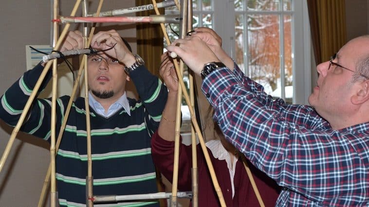 Two men putting the finishing touches to a rollercoaster out of bamboo canes during an exercise