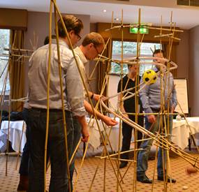 A team completing some Indoor team building activities for large groups where they need to build a rollercoaster out of the materials provided.