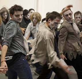 A group of people dressed up as zombies and performing the Thriller dance and taking part in team building activities for a large groups