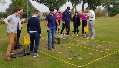 A team guiding their blindfolded colleague through 'hazard area' during a Crystal Challenge outdoor team building activity