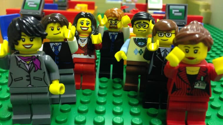Lots of LEGO figures standing together with their arms raised.